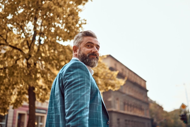 A senior businessman in a suit walking around the city after work.