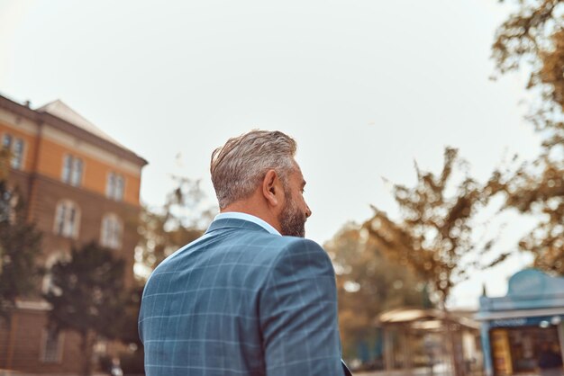 A senior businessman in a suit walking around the city after work.