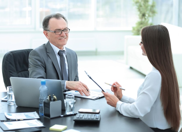 Senior businessman talking to his young assistant at the desk