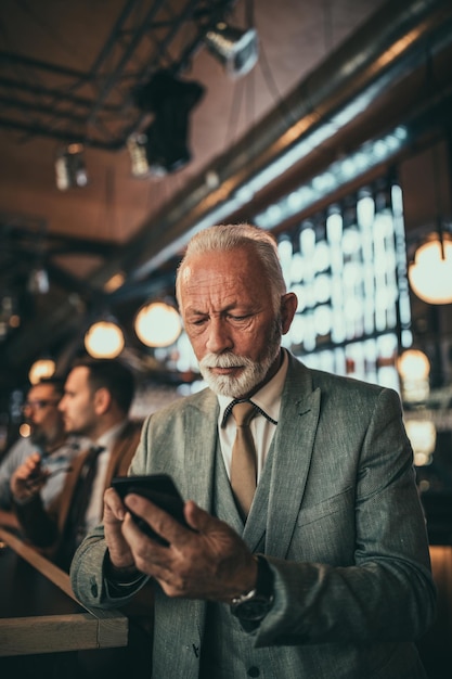 Senior businessman using phone at the pub