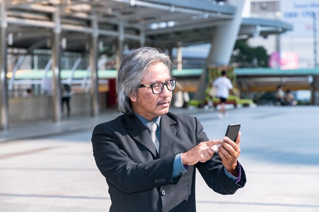 Senior businessman using smart phone in city