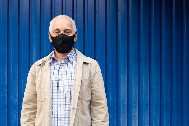 L'uomo d'affari maggiore indossa la maschera protettiva contro le malattie infettive e l'influenza sull'azzurro