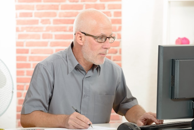 Foto uomo d'affari senior con gli occhiali rossi che lavorano al computer