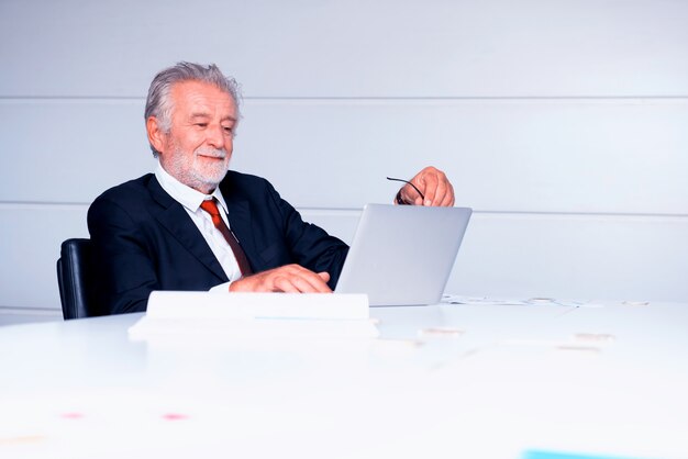 senior businessman working in office. Looking on business profits chart on laptop.