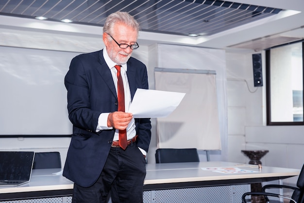 senior businessman working in office. Looking on business profits chart on paper.