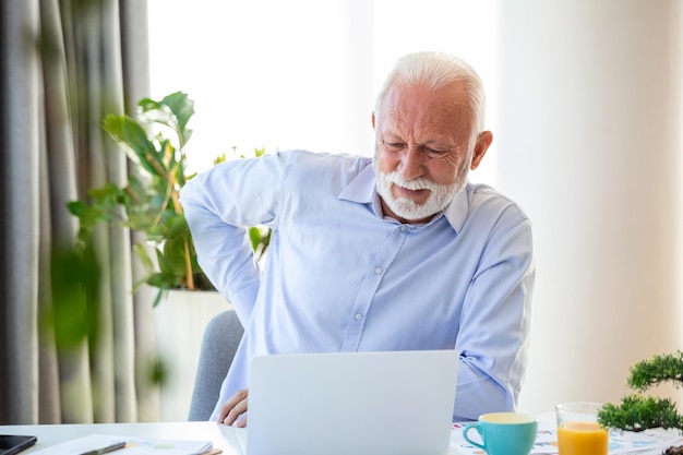 Senior businessman working sitting at desk suffers from lower back pain Damage of intervertebral discs spinal joints compression of nerve roots caused by wrong posture and sedentary work