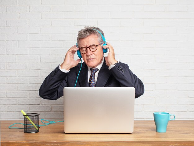 Senior businessman working  with his laptop and listening music 