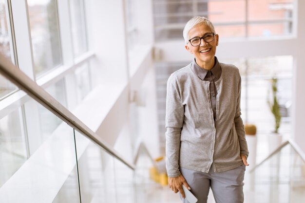 Senior businesswoman standing on the stairs in office