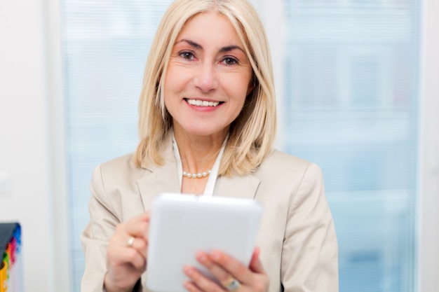 Senior businesswoman with a tablet in her office