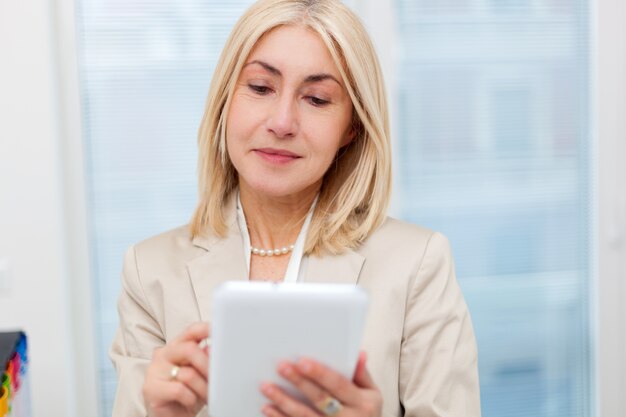 Senior businesswoman with a tablet in her office