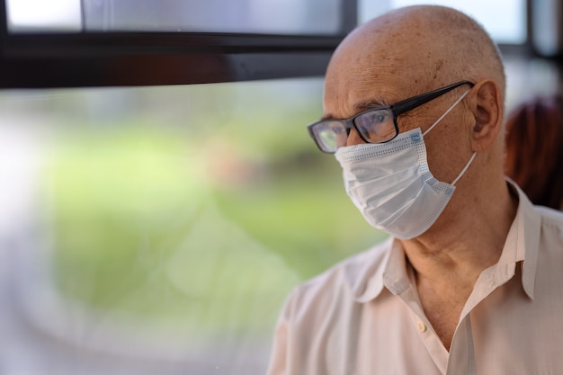 Senior buspassagier die voor de gezondheid zorgt en een masker draagt