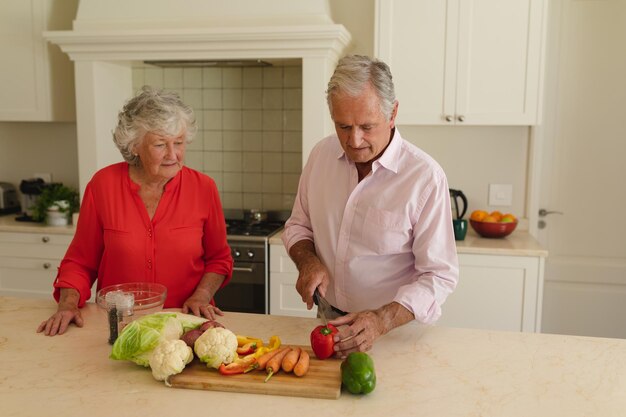 Senior caucasian couple cooking together and talking in kitchen. retreat, retirement and happy senior lifestyle concept.