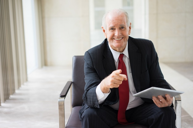 senior Caucasian executive sitting in armchair with digital tablet