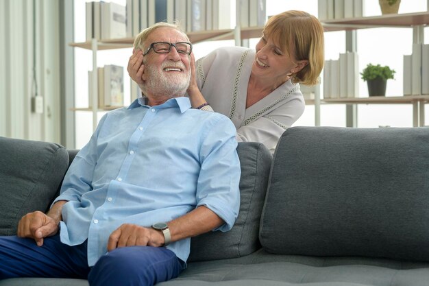 Uomo caucasico anziano che fa un massaggio per sua moglie nel soggiorno