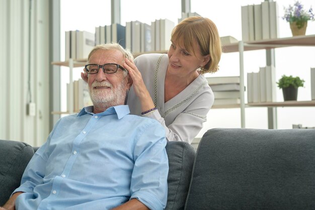 Senior caucasian man doing massage for his wife in living room