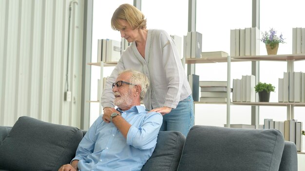 Senior caucasian man doing massage for his wife in living room