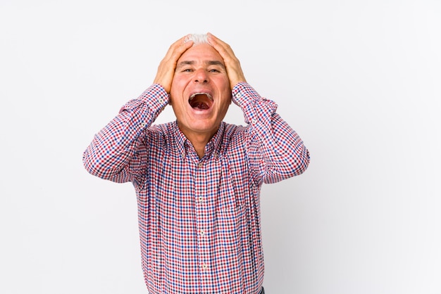 Senior caucasian man isolated laughs joyfully keeping hands on head. Happiness concept.