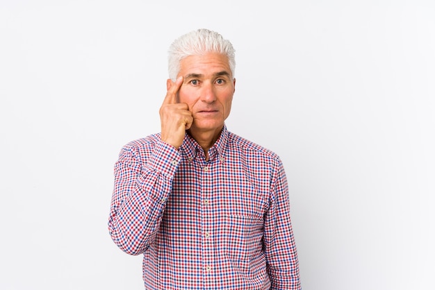 Senior caucasian man isolated pointing temple with finger, thinking, focused on a task.