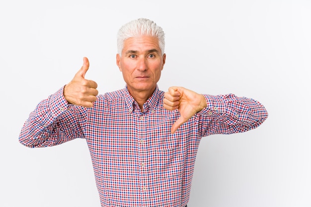 Senior caucasian man isolated showing thumbs up and thumbs down, difficult choose concept