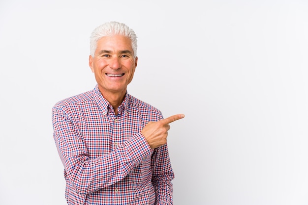 Senior caucasian man isolated smiling and pointing aside, showing something at blank space.