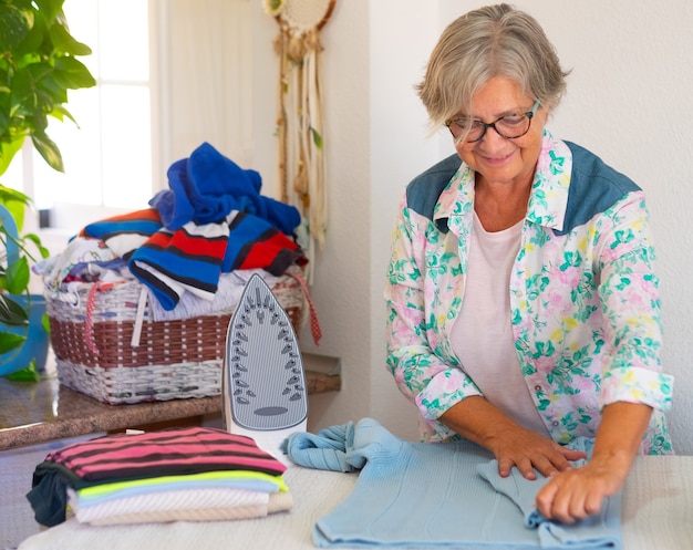 Senior donna caucasica a casa a stirare in un angolo