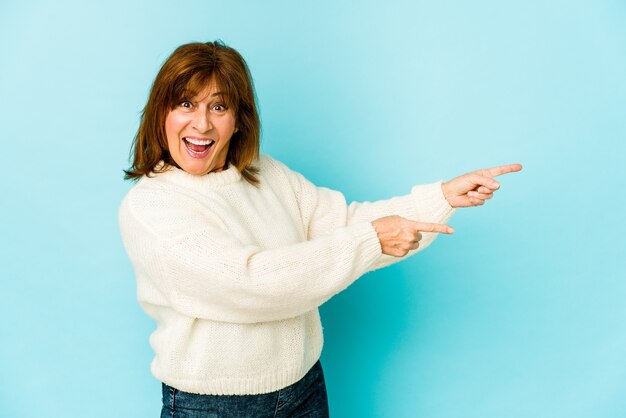 Senior caucasian woman isolated pointing with forefingers to a copy space, expressing excitement and desire.