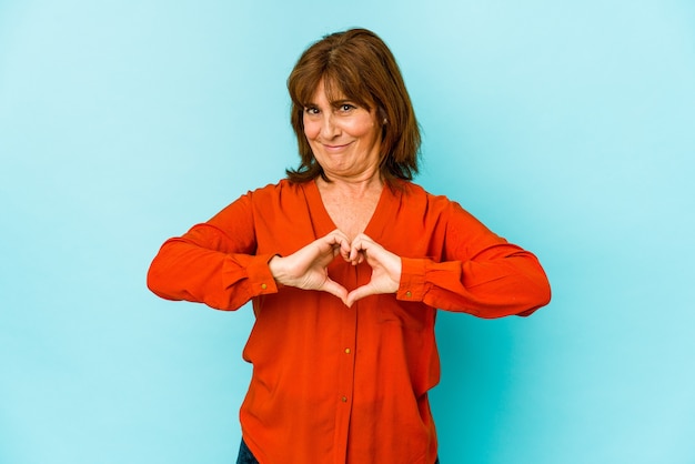 Senior caucasian woman isolated smiling and showing a heart shape with hands.