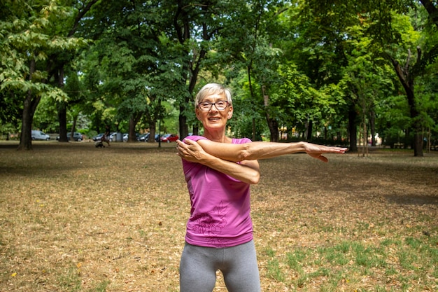 Senior caucasian woman stretching her fit body warming up and preparing for training in nature.