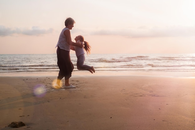 Anziani e bambini che camminano al tramonto sulla spiaggia del mare