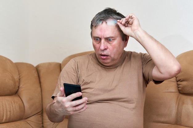 Senior citizen sitting on the couch understands the gadget mastering smartphone