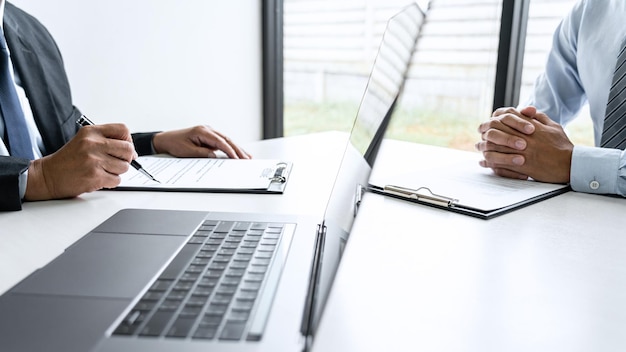 Senior committee manager reading a resume during a job interview, Employer interviewing to ask young male job seeker for recruitment talking in office.