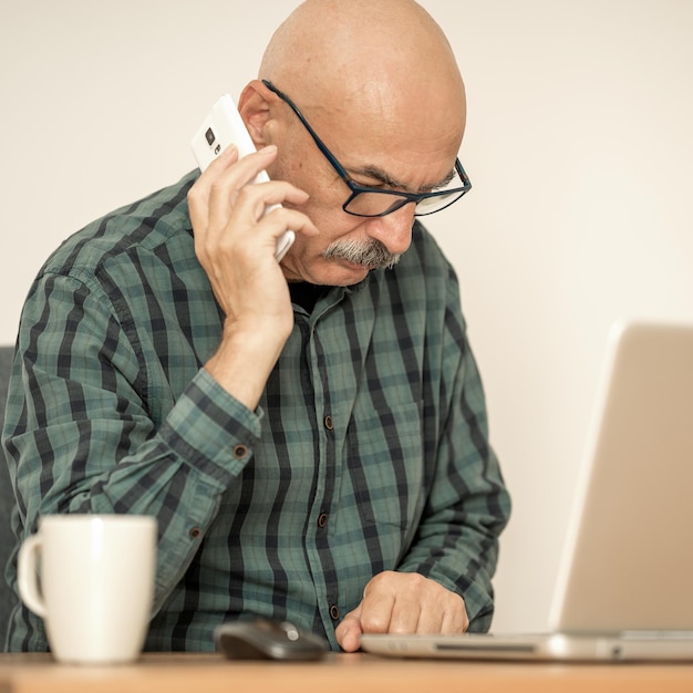 Senior confident man working in office and making phone call