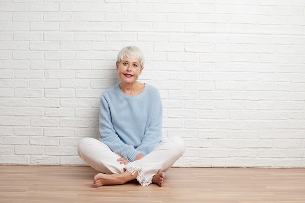 Senior cool woman against white brick wall background