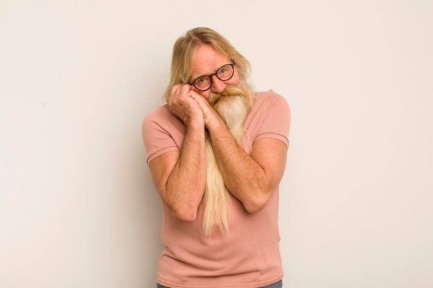 Senior coole bebaarde man die verliefd is en er schattig schattig en gelukkig uitziet, romantisch glimlachend met de handen naast het gezicht