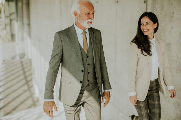 Senior corporate business professional en zijn jonge vrouwelijke collega klimmen op de trap in de kantoorgang