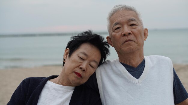 Senior couple at beach against sky during sunset