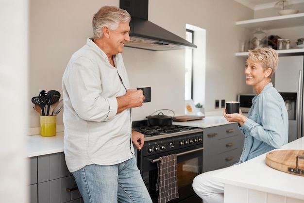 Senior couple coffee and talking in kitchen with mug beverage or drink at home Retirement smile and elderly happy man and woman drinking tea speaking discussion or communication in house