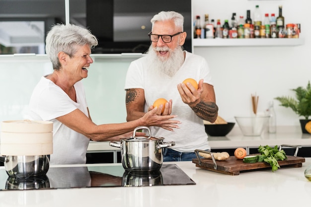 Senior couple cooking at home while preparing vegetarian lunch Focus on woman hand