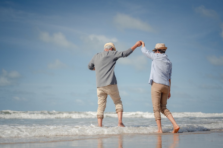 Photo senior couple dancing on the beach at sunny day. plan life insurance with the concept of happy retirement.