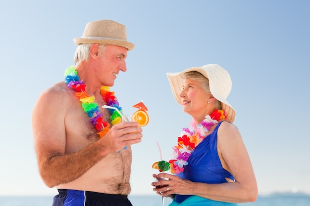 Senior couple drinking a cocktail on the beach