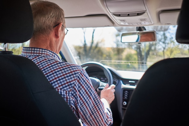 Senior couple driving car during road trip. View from back.