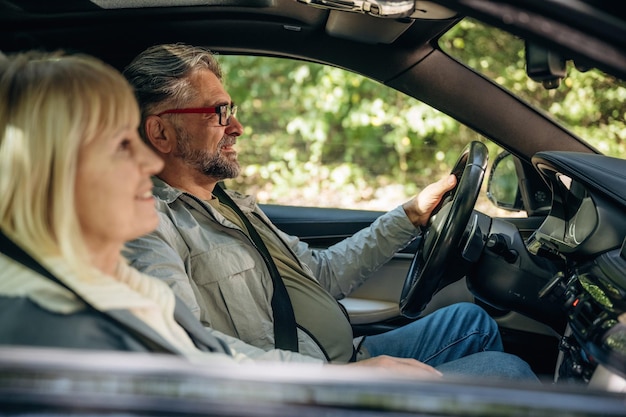 Senior couple driving in the modern car at summertime