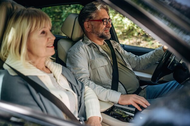 Senior couple driving in the modern car at summertime