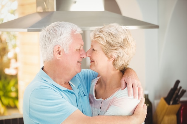 Coppie senior che abbracciano mentre toccando naso in cucina