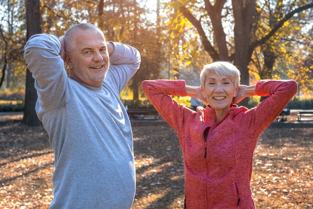 秋の公園で年配のカップルが一緒に運動