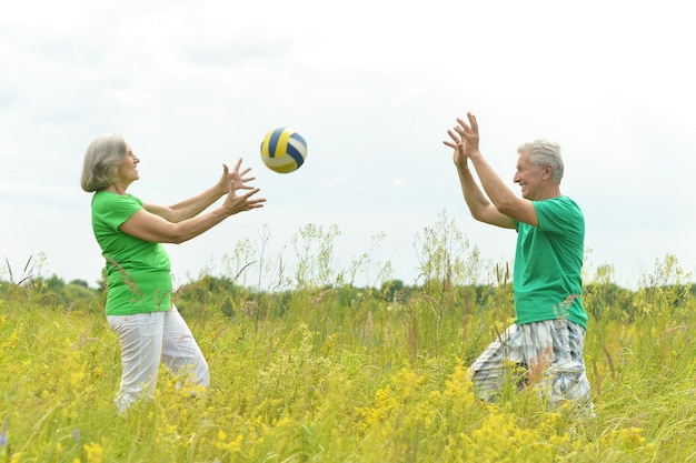 Senior couple in field with ball in summer