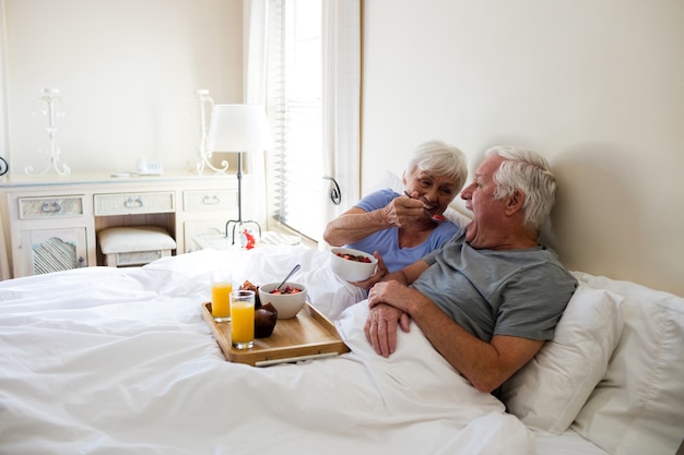 Senior couple having breakfast in the bedroom at home