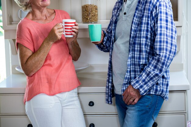 自宅のキッチンでコーヒーを飲んでいる年配のカップル