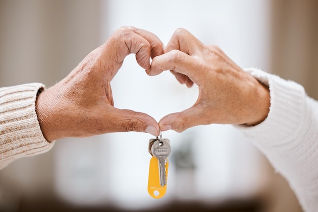 Senior couple heart hands and keys for new home success and bonding with love care and support Closeup elderly people and hand sign together in house apartment or home with excited homeowner