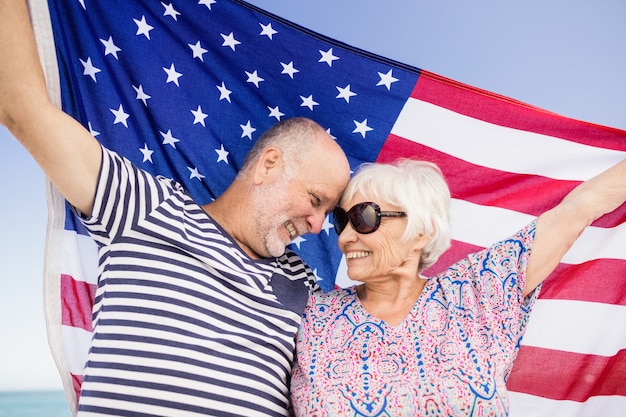 Пожилые супружеские пары, держа американский флаг вместе